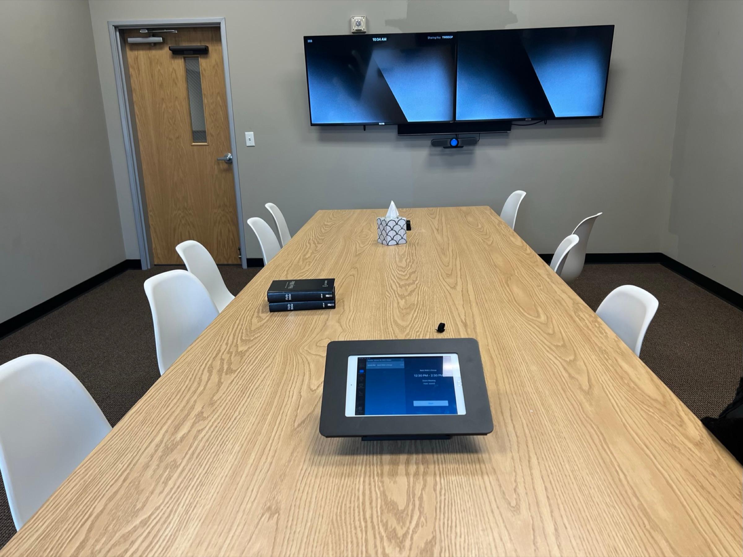A conference room set up with dual displays and video conferencing equipment for team meetings and training sessions