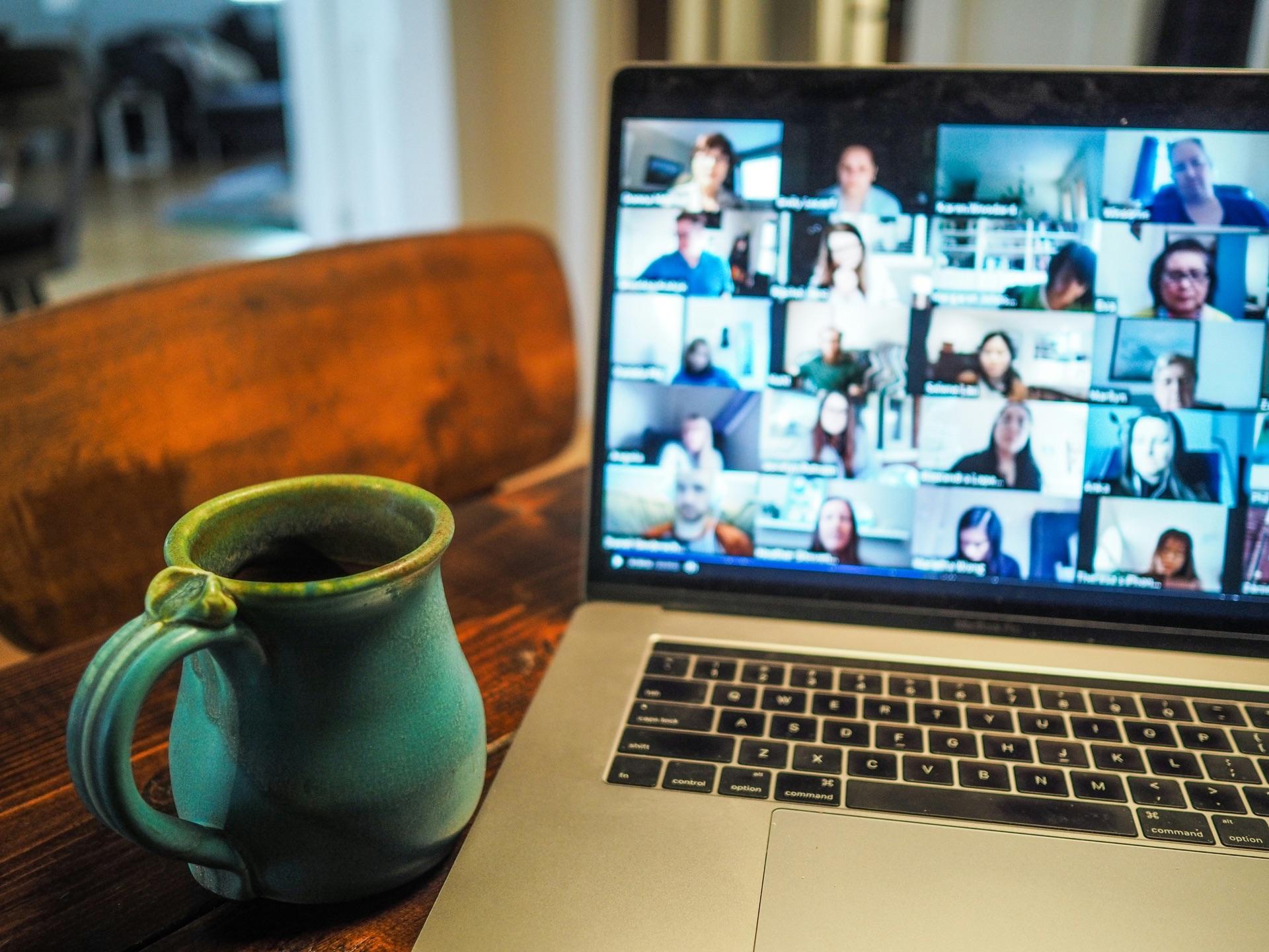 A consultant on a video call with a client from a laptop and coffee mug