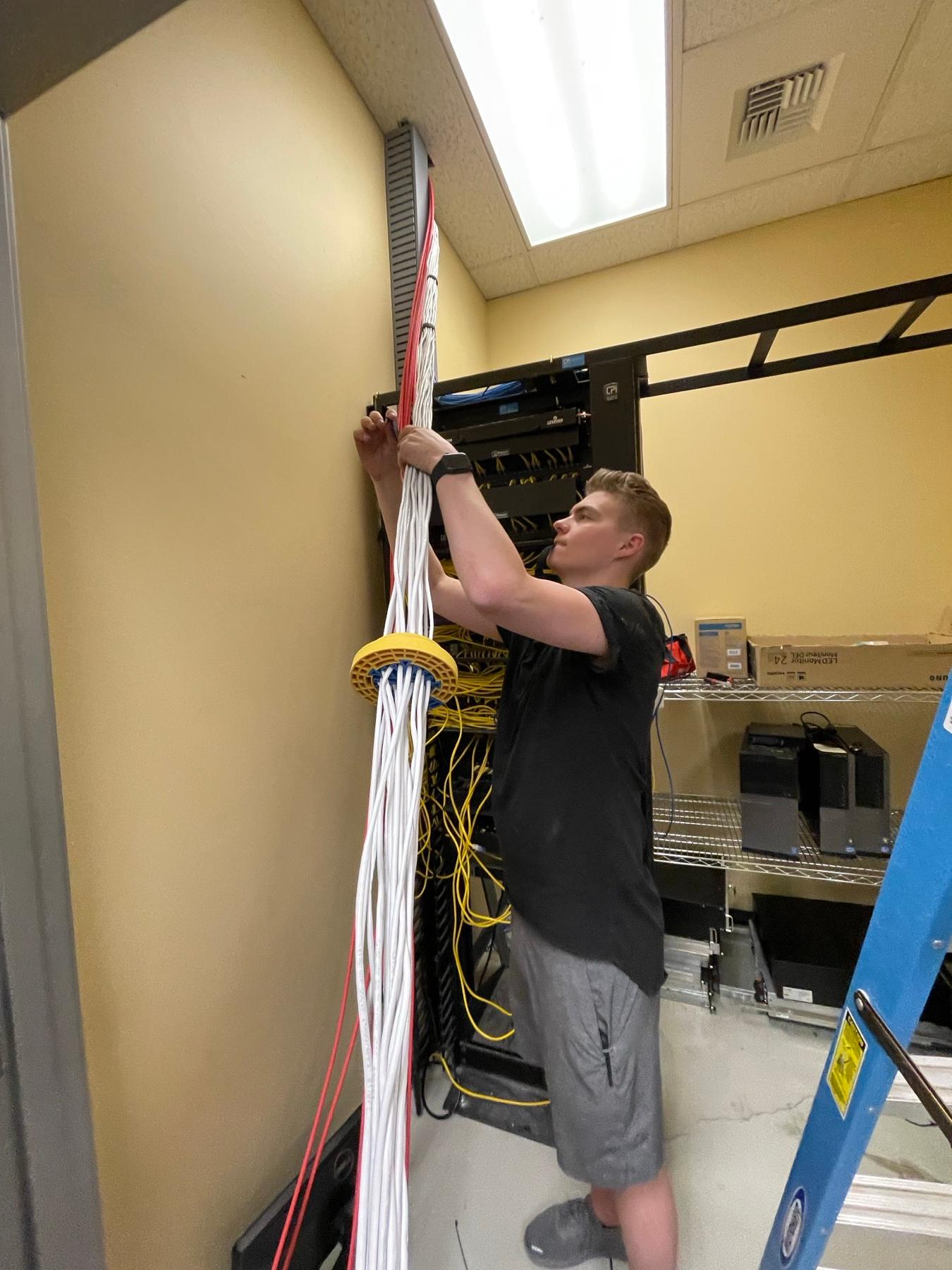 A FinWell technician running cable in a network closet
